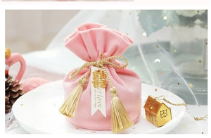 Close-up of pink velvet wedding favor bag with gold tassel and metal Xi character