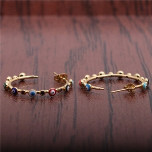 Macro shot of gold hoop earrings with multi-colored evil eye beads and metal spheres