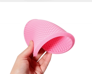 Flexible pink silicone coaster with honeycomb texture shown being folded by hand