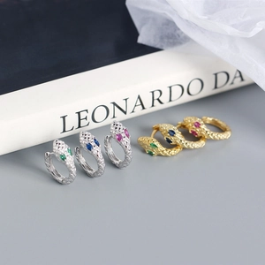 Detailed view of snake hoop earrings in gold and silver with colorful gemstone eyes