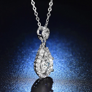 Close-up of heart-shaped silver moissanite pendant with halo diamonds on blue background
