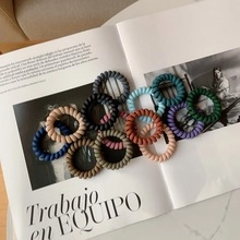 Close-up of colorful spiral telephone wire hair ties scattered on a magazine