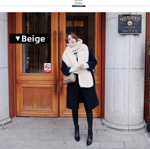 Detail of chunky beige knit scarf styled with a navy wool coat and black leather ankle boots