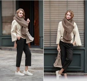 Street style shot of a woman wearing a thick brown chunky knit scarf in the city