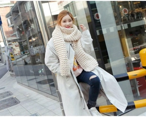 Detail of off-white chunky knit scarf showing the thick texture on a model outdoors