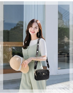 Close-up of black quilted leather crossbody bag with ethnic embroidered wide strap