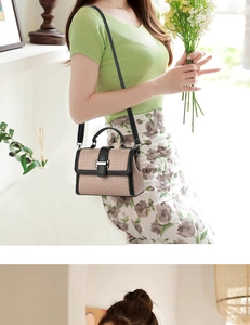 Detail of woven texture handbag with black leather trim and silver metal buckle
