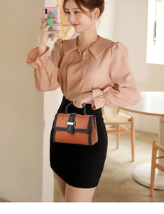 Detail of woven mini bag with orange body, black trim, and silver metal buckle