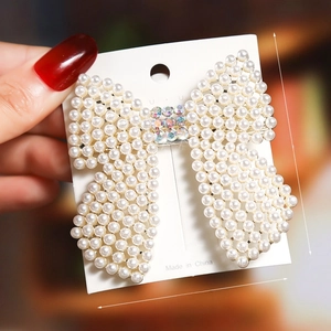 Detailed view of pearl bow hair clip with sparkling rhinestones, 7cm by 6.5cm size