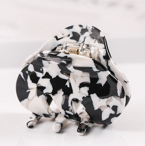 Macro shot of acetic acid hair claw clip with black and white marble pattern and gold spring