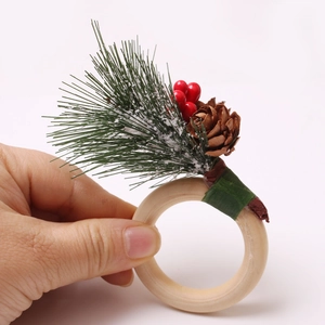 Detail of a wooden napkin ring decorated with pine cones, red berries and green needles