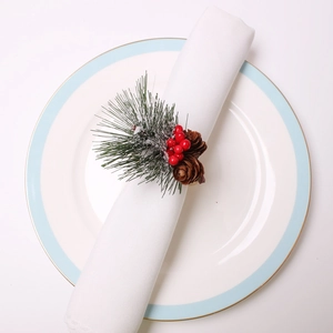 Macro view of Christmas napkin ring with pine cones, red berries and green pine needles