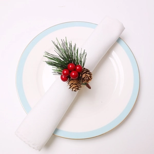 Detail of pine needles, red berries, and pinecone on a festive napkin ring