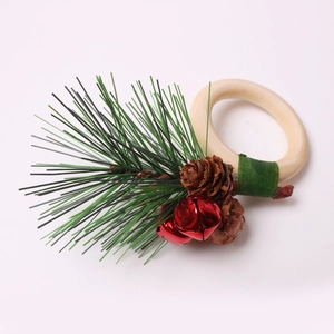 Close-up of Christmas napkin ring with pine needles, pinecones, and red bells on wood