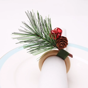 Close-up of pine cone and red bell Christmas napkin ring on a white table setting