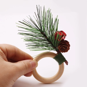 Christmas napkin ring with pine cones, red bells and wooden circle on white background