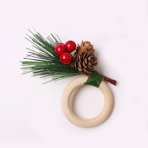 Detail of wooden napkin ring with artificial pine needles, red berries and pine cone
