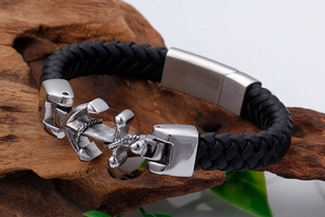Detail of black woven leather strap with silver stainless steel anchor clasp on wood