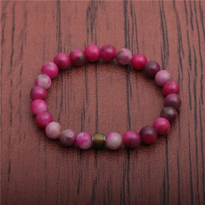 Close-up of handmade mood beads bracelet with pink marble stones on dark wood background