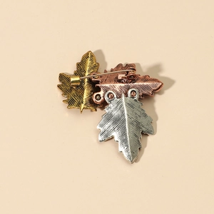 Back view of retro metal leaf brooch in gold, silver, and bronze tones with safety pin clasp