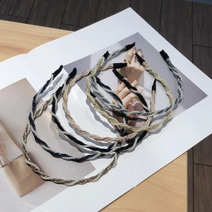 Cinco elegantes diademas trenzadas con perlas en negro, oro y plata sobre madera
