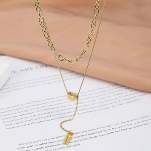Detail of gold double-layer necklace with paperclip chain and rectangular pendant