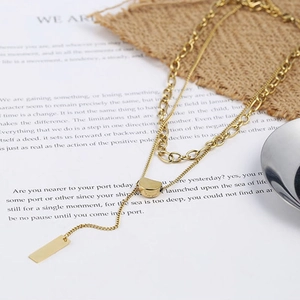 Close-up of golden double-layer stacked necklace with geometric pendants on a vintage book