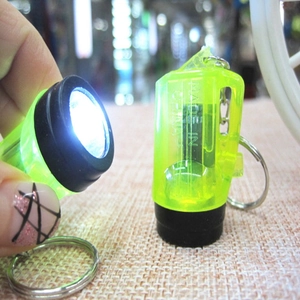Mini LED flashlight keychain in neon green transparent casing with bright light