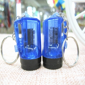 Close-up of two blue transparent mini LED flashlight keychains on burlap texture