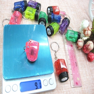 Mini multi-color LED flashlight keychain on scale showing 9.1g weight for size reference