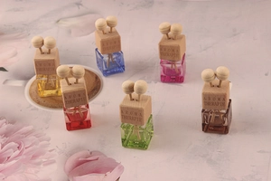 Group of six colorful glass car perfume bottles with wooden caps on a marble surface
