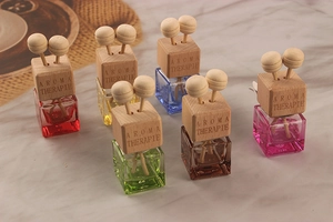 Colorful square glass car perfume bottles with wooden caps on a marble surface