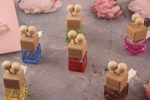 Detail of square glass car perfume bottles with wooden caps and multi-colored liquids