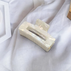 Detail of ivory acetate rectangular hair claw clip with pearl marble texture and spring