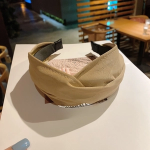Detail of beige faux leather headband with twisted design and fine stitching details