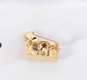 Back view of gold camera brooch showing safety pin clasp and smooth metal texture