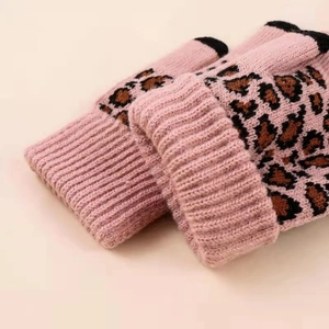 Macro view of pink knitted leopard print gloves with ribbed cuffs and touchscreen tips