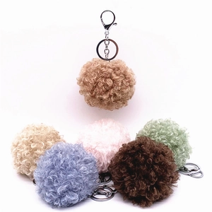 Detailed view of colorful curly faux fur pom-pom keychains in soft pastel tones