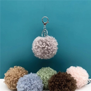 Close-up detail of cute curly plush pompom keychains in various soft pastel colors