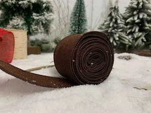 Close-up of brown burlap ribbon roll with winter pine cone and mini Christmas tree
