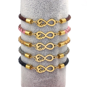 Detail of woven bracelets with gold infinity love charms on a grey display stand