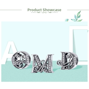 Macro detail of silver O, M, and D alphabet charms with vintage floral pattern and zircon