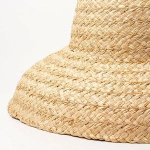 Macro shot of hand-woven natural raffia texture on a bell-shaped wide brim sun hat
