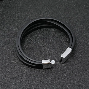 Pulsera multicapa de cuero negro con cierre magnético plateado sobre fondo oscuro sólido