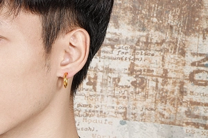 Close-up of minimalist polished gold hoop earrings worn on ear with vintage backdrop