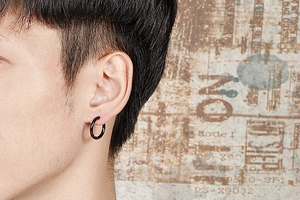 Close-up of a minimalist black stainless steel hoop earring worn by a male model