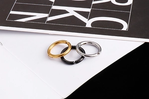 Detailed view of polished stainless steel ear clips in gold, black, and silver colors