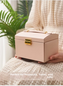 Pink three-layer jewelry box with gold handle and vintage lock, held by hands