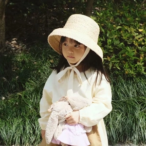 Detailed view of children's raffia straw hat with strap design and woven texture