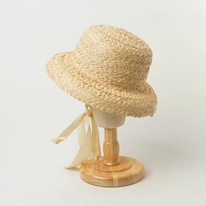 Classic straw sun hat for children with beige ribbon on a wooden display stand